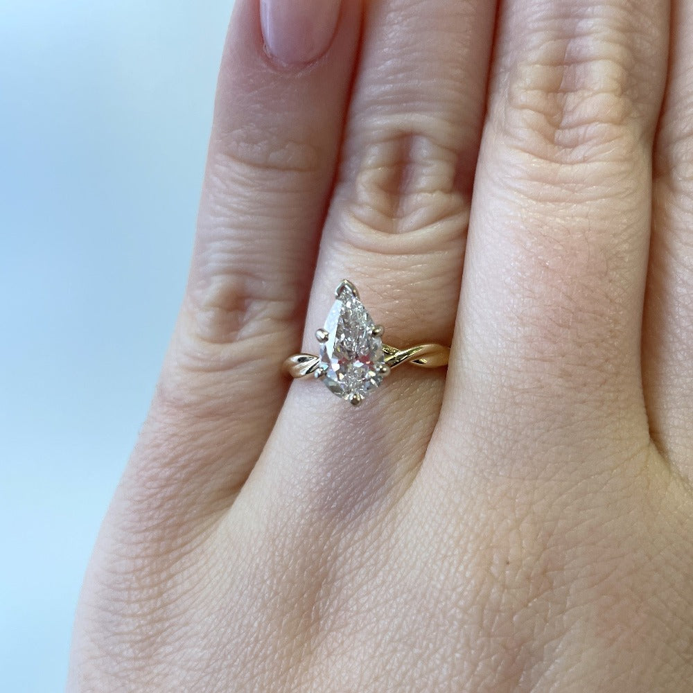 up close detail view of 14ky pear cut diamond solitaire engagement ring on model