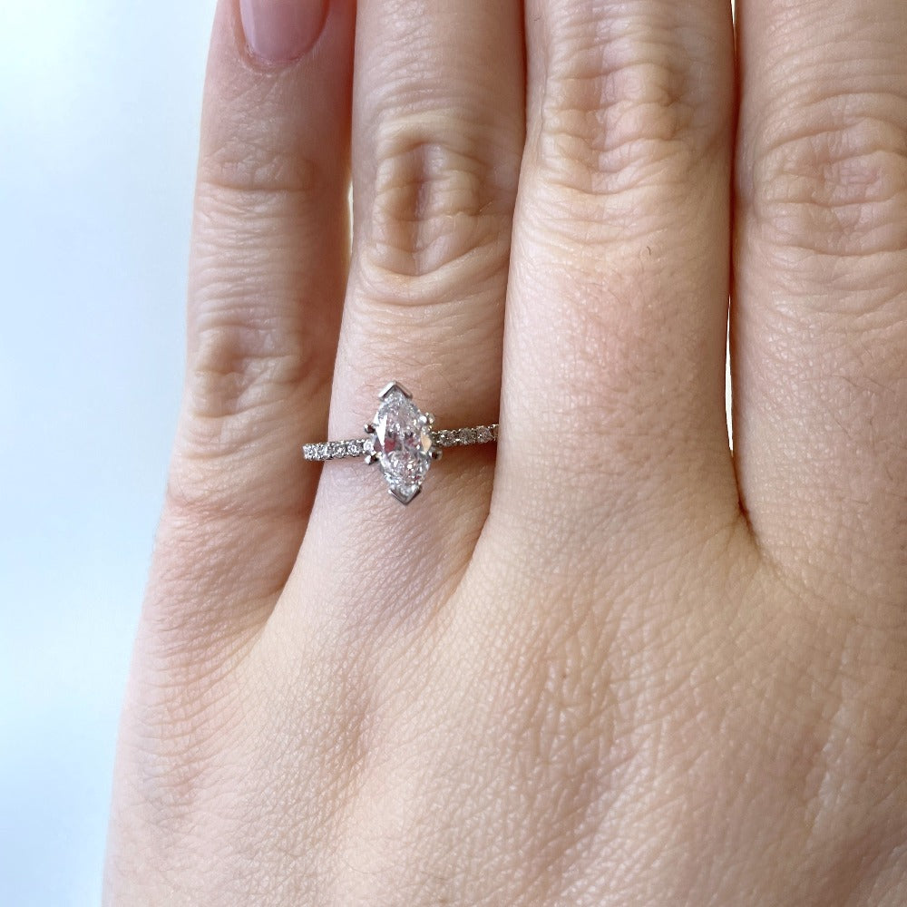 up close, detail view of 14kw marquise cut diamond accented solitaire engagement ring on model