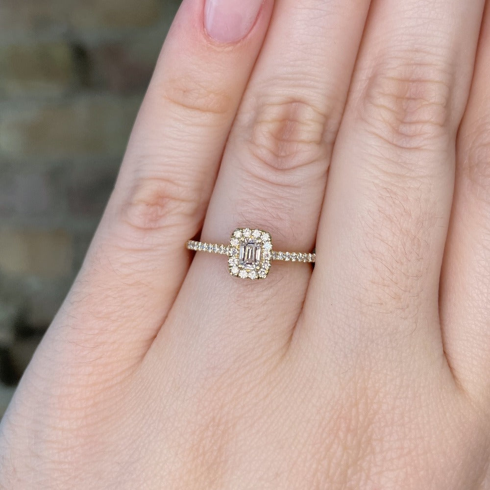closer view of 14ky emerald cut halo style engagement ring on model