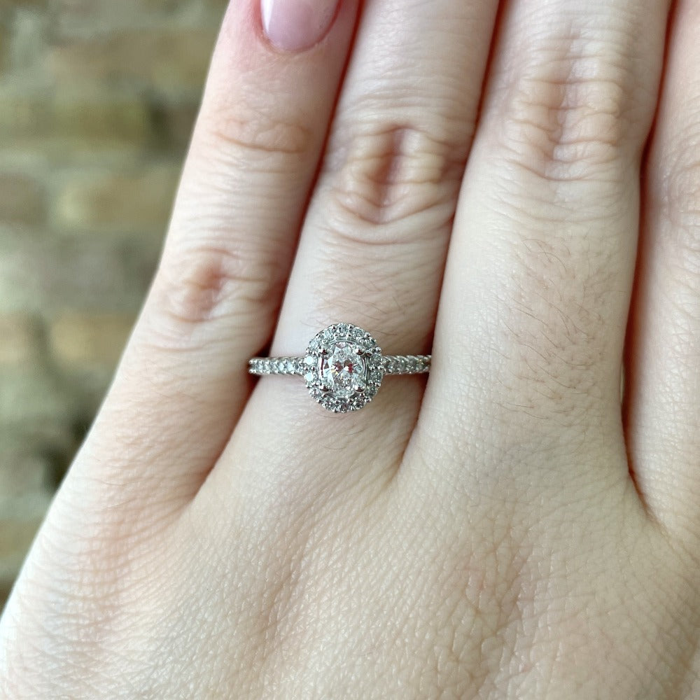 closer, more detailed view of oval halo style ring on model's hand.