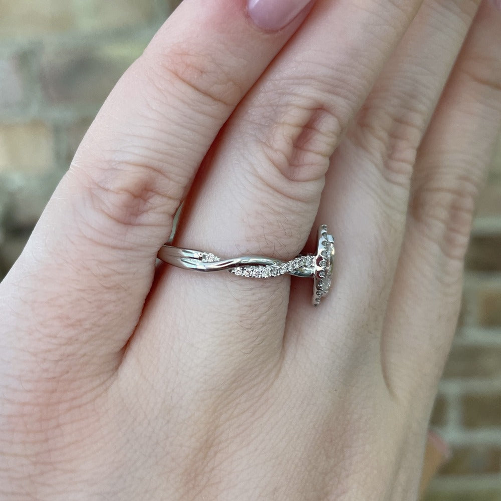 side view of 14kw marquise halo style ring with twisted shank on model