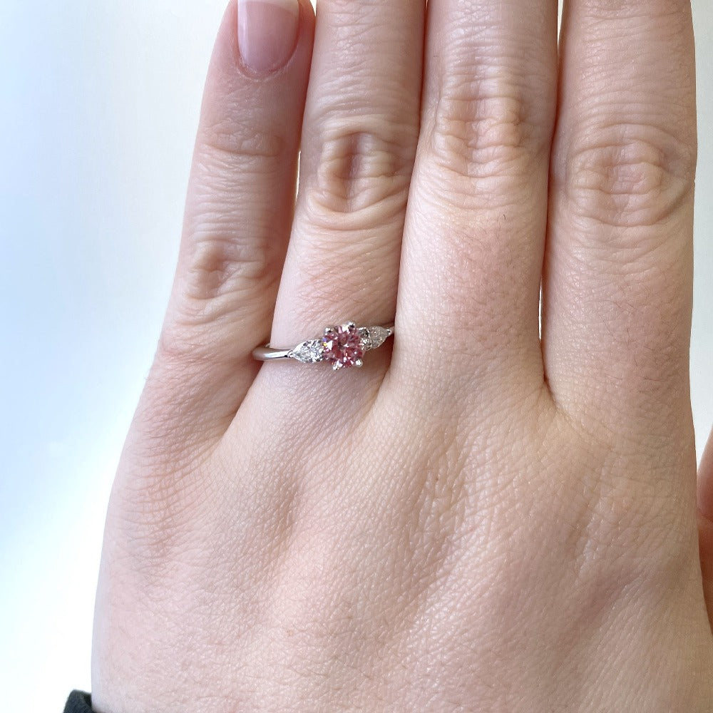 up close detail view of treated pink diamond engagement ring on models hand