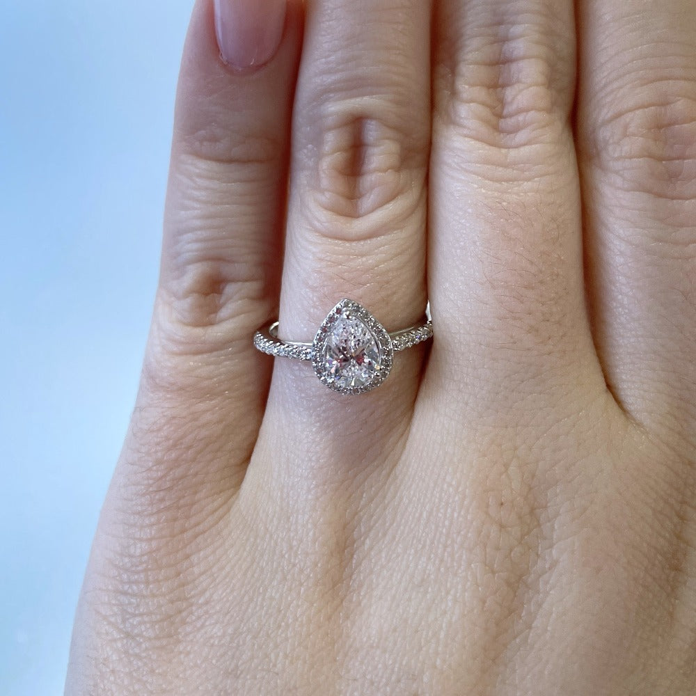 up close detail view of 14kw pear cut halo style engagement ring on model