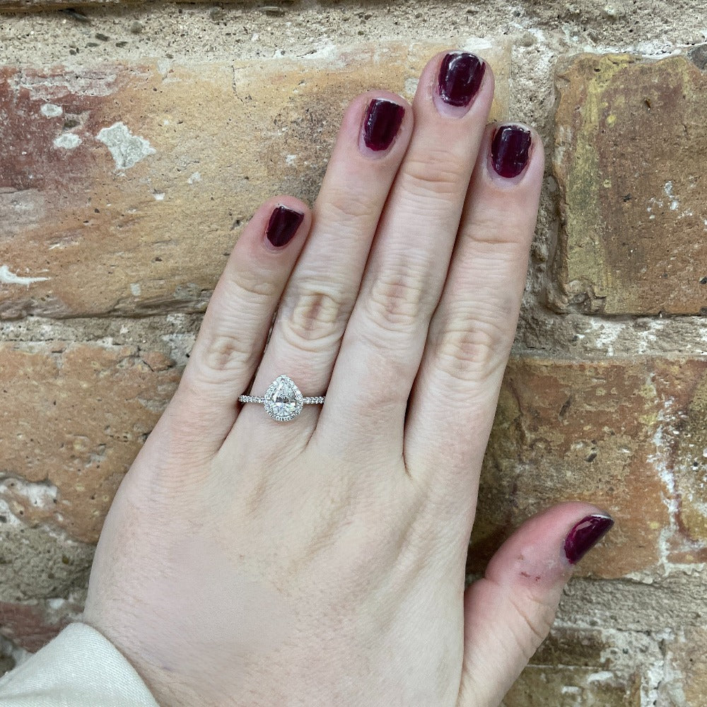 14kw diamond engagement ring with halo and pear cut center. picture shows ring on model's hand.
