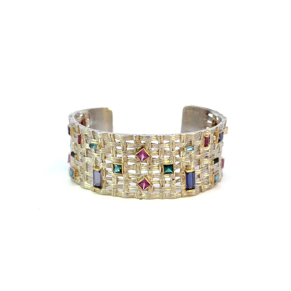 sterling silver cuff bracelet with lattice design and colored gemstone accents set in yellow gold.