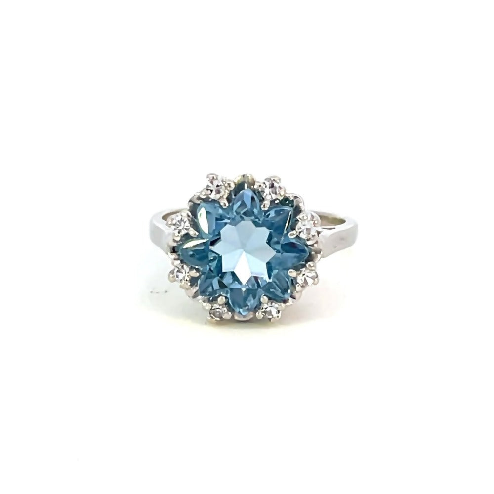 front view of 14k white gold ring with flower cut blue center stone and white stone accents