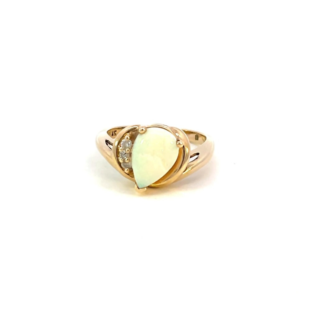 front view of 14k yellow gold ring with pear cut opal center stone and three accent diamonds