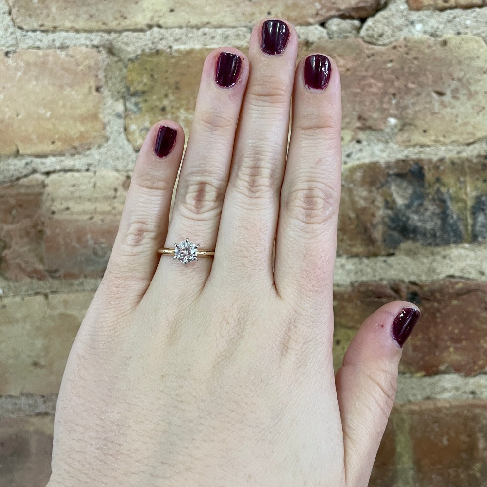 1.01 carat round diamond solitaire engagement ring with yellow gold band on the hand of a model