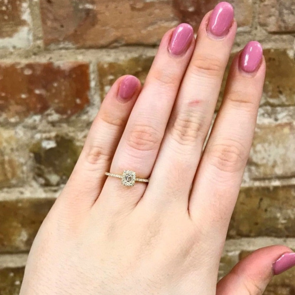 4KY Halo-Style Diamond Engagement Ring with Emerald Cut Center Stone on hand