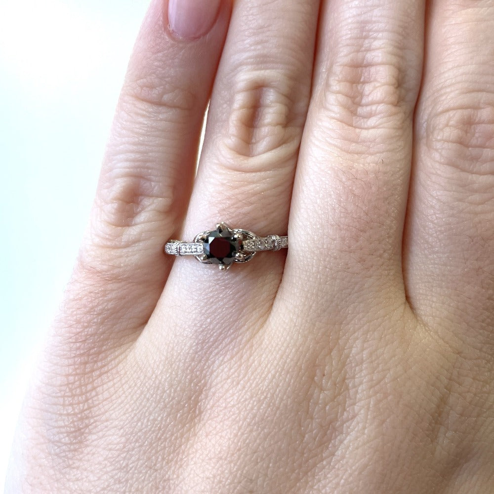 up close detail view of 14kw black diamond engagement ring on models hand