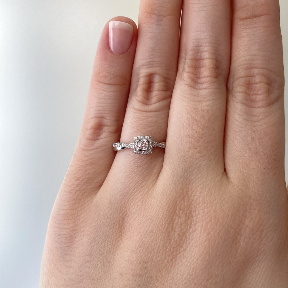 up close view of 14kw halo style engagement ring on model's hand shot in natural light.